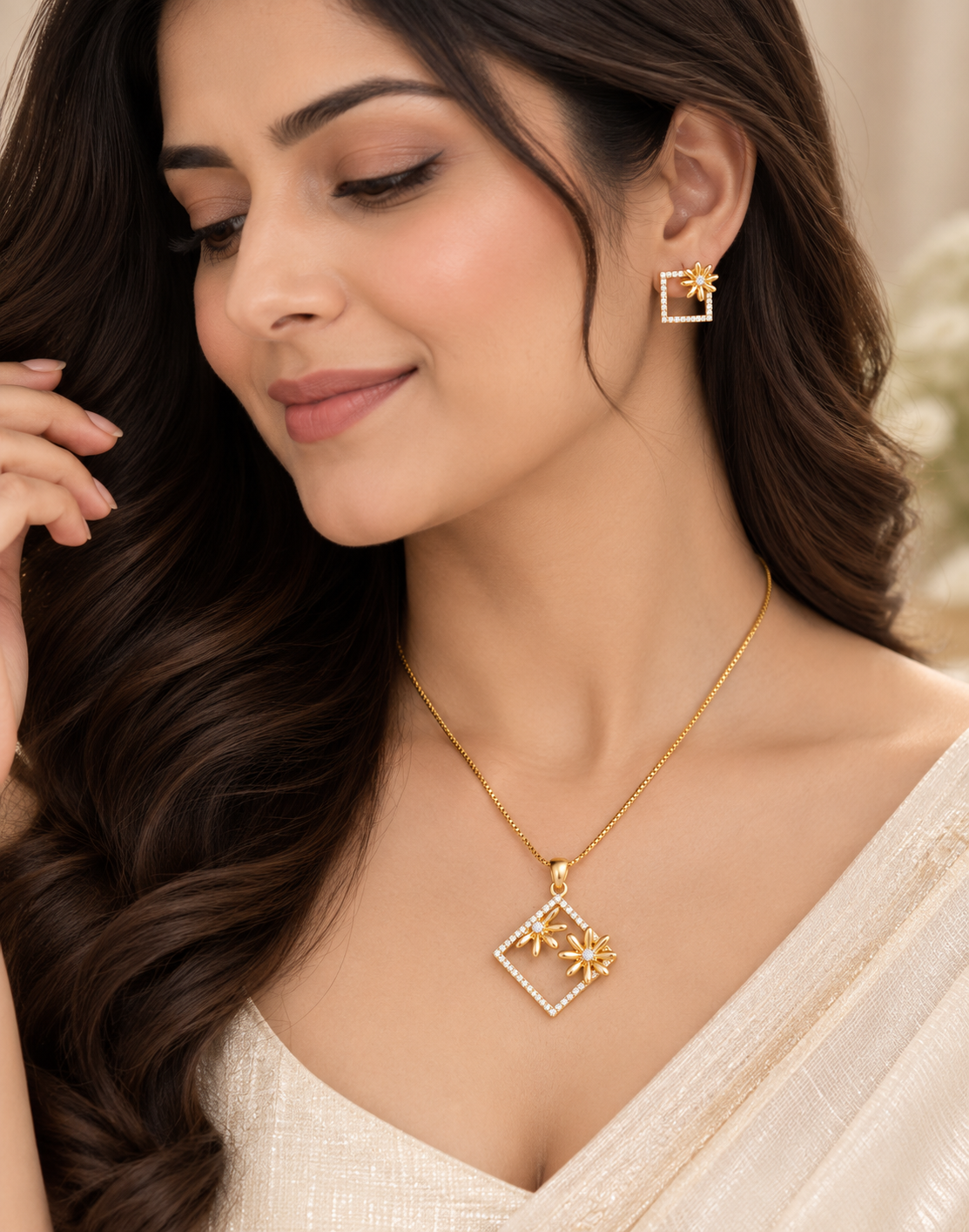 A woman wearing a gold square pendant necklace with a small flower detail and a matching gold square stud earring, shown in a close-up portrait.