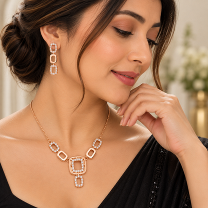 A woman wearing a rose gold geometric link necklace and matching drop earrings with clear pavé stones, shown in a close-up portrait.