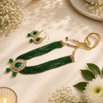 Green beaded necklace set with teardrop pendant and matching earrings flat lay
