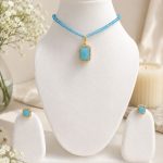 Sky blue pendant necklace set displayed on white jewellery stand