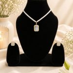 White crystal pendant necklace set displayed on black jewellery stand