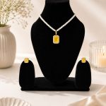 Yellow crystal pendant necklace set displayed on black jewellery stand
