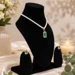Flat lay of green crystal pendant necklace and matching stud earrings
