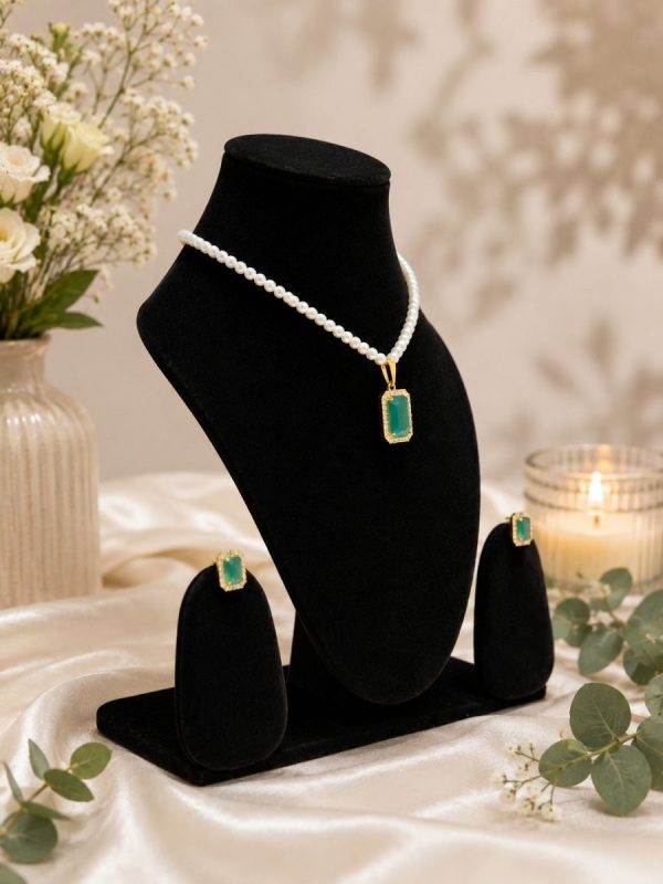 Flat lay of green crystal pendant necklace and matching stud earrings
