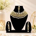 Gold plated Kundan pearl choker necklace set displayed on jewellery stand