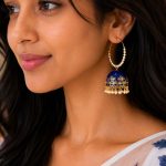 Woman wearing blue pearl hoop jhumka earrings with enamel and pearl design