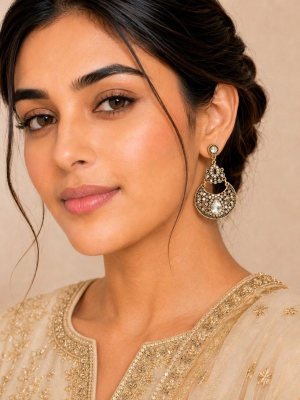 Woman wearing antique gold Kundan dangle earrings with white stone detailing