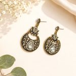 Close-up view of antique gold ethnic earrings with white teardrop stone