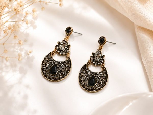 Close-up view of antique gold black stone dangle earrings front view on flat