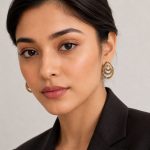 Woman wearing antique gold stud earrings with elegant blazer