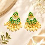 Gold plated green stone pearl chandbali earrings on decorative background